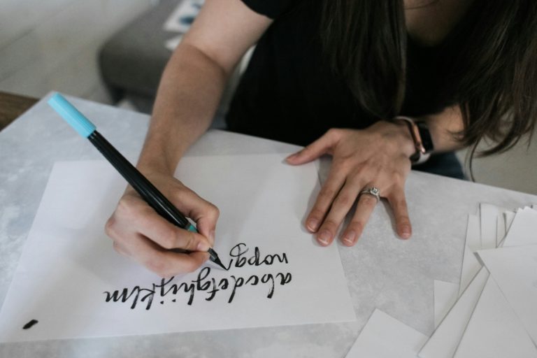 A person writing the alphabet on a sheet of paper